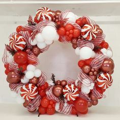 a wreath made out of red and white candy canes, christmas decorations, and balloons