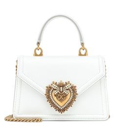 Dolce & Gabbana's Devotion bag is crafted from smooth leather and works a structured silhouette with a ladylike top-handle. The design is adorned with gleaming golden hardware â" including a handmade heart in metal alloy, with an inlay of faux-pearls â" which stand out against its snow white base. | Dolce & Gabbana Devotion Small leather shoulder bag Fancy Bags, Dolce E Gabbana, Dolce & Gabbana, Handle Bag, Leather Satchel, White Bag, Leather Top, Fashion Handbags, Small Bags