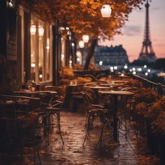 an empty restaurant with tables and chairs in front of the eiffel tower at night