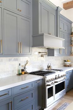 a kitchen with blue cabinets and white counter tops, gold pulls on the hoods