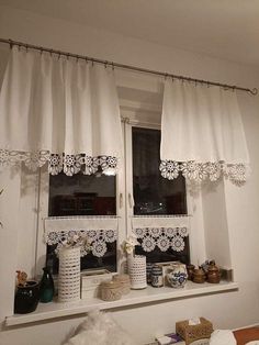 a window with white curtains and lace on the valance, along with other items