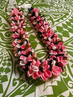 pink and white flowers are arranged in the shape of a heart on a green patterned tablecloth