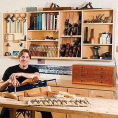 a man is sitting at a table with some woodworking tools in front of him