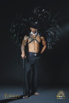 the man is wearing a top hat with feathers on his head and holding a cane