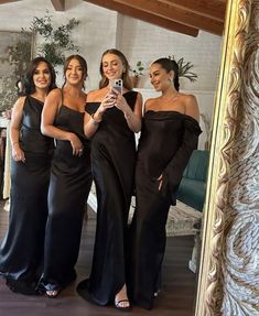 four women in black dresses are taking a selfie with their cell phone while standing next to each other