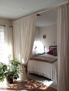 a bed sitting under a window next to a potted plant in front of it