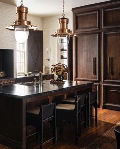 a large kitchen with an island in the middle and two pendant lights hanging from the ceiling