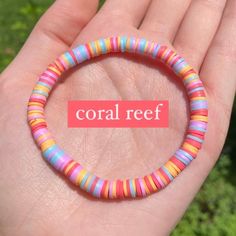 a hand holding a colorful bracelet with the word coral reef on it's side