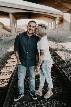 a man and woman standing on train tracks