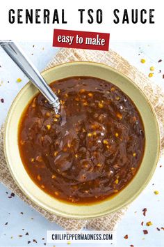 a bowl filled with chili sauce on top of a white table next to a spoon