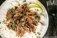 shredded meat and rice on a plate with lime wedges