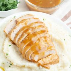 a white plate topped with mashed potatoes covered in gravy and sliced chicken