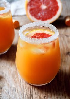 two glasses filled with orange juice on top of a wooden table