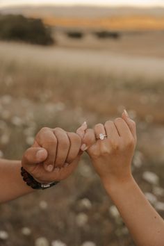 two people holding hands in the middle of a field