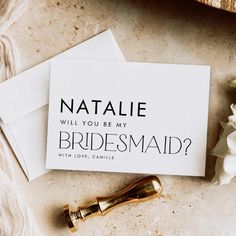 a note with the words natalie will you be my bridesmaid? next to some flowers