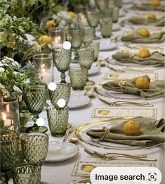 a long table is set with green glassware and lemons on the place settings