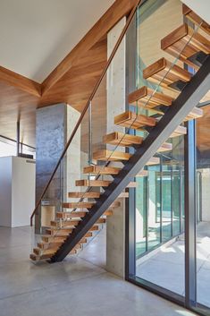 a modern staircase with glass railing and wooden handrail