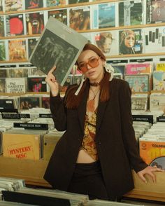 a woman is holding up a book in front of her face as she stands at a record store