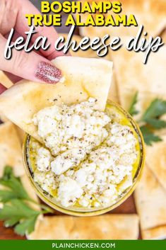 a hand dipping feta cheese dip into pita bread with herbs on the side