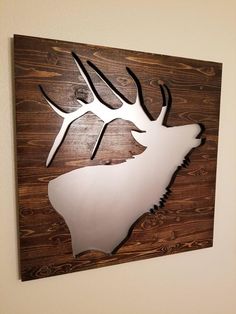 a metal deer head mounted to the side of a wooden wall hanging on a wall