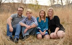 three adults and two children sitting in tall grass