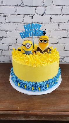 a yellow and blue birthday cake with two minion characters