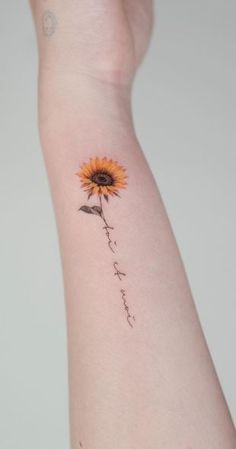 a small sunflower tattoo on the left arm with words written in cursive writing