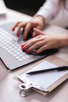 a woman is typing on her laptop with a pair of scissors in front of her