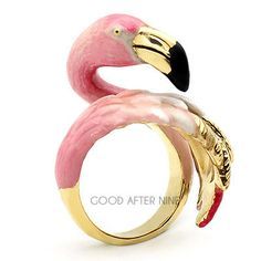 a pink flamingo ring sitting on top of a white table next to a black and gold band