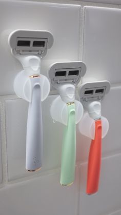 three toothbrushes are hanging on the wall next to each other with two different attachments