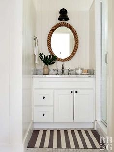 a bathroom with a sink, mirror and striped rug on the floor in front of it