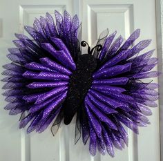 a purple and black wreath hanging on the front door