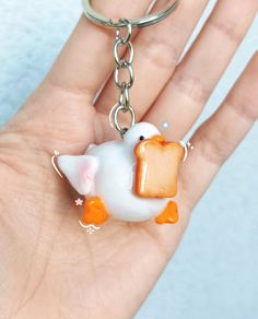 a hand holding a keychain with a bird on it