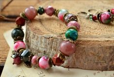 Bright color gemstone bracelet. Made from large natural beads of jade, faceted pink rhodonite, strawberry quartz, chrysocolla, mookaite and faceted Indian agate. Decorated with a miniature Czech glass pendant and antique bronze colored fittings.  The bracelet is available in 7 sizes, depending on the size of the wrist: Wrist - 14-14.5 Centimeters (5.51-5.70 inch). Wrist - 15-15.5 Centimeters (5.90-6.10 inch). Wrist - 16-16.5 Centimeters (6.29-6.49 inch). Wrist - 17-17.5 Centimeters (6.69-6.88 in Bohemian Pink Agate Bracelets, Pink Agate Round Bead Crystal Bracelet, Pink Bohemian Bracelets With Faceted Beads, Pink Agate Beaded Bracelets With Natural Stones, Handmade Pink Agate Bracelets, Pink Agate Hand-strung Bracelets, Silver Heart Jewelry, Aventurine Jewelry, Pink Beaded Bracelets