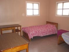 a bedroom with two beds and desks in it