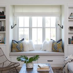 a living room filled with lots of furniture and bookshelves next to a window