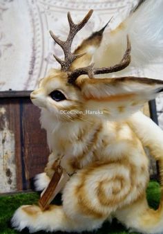 a stuffed animal with antlers on it's head is sitting in the grass