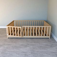 a wooden crib in a room with light blue walls and wood flooring on the side