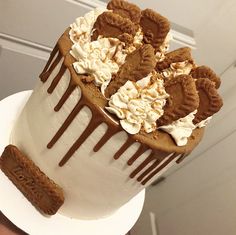 a white cake with chocolate cookies and cream frosting on top is being held up by someone's hand