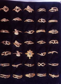 an assortment of gold rings and brooches are displayed on a black velvet case