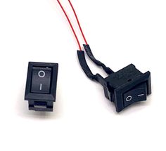 two pieces of black electrical equipment on a white surface, one with red wire and the other without wires