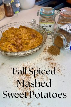 a bowl filled with mashed sweet potatoes on top of a table next to spices