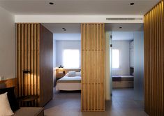 a bedroom with wooden slats and a bed in the background, as seen through two partitions