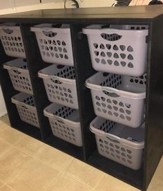 several plastic laundry baskets stacked on top of each other in front of a black cabinet