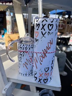 two coffee cups sitting on top of a white table next to each other with writing on them