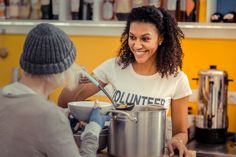 a woman is smiling as she prepares food in the kitchen with another woman behind her