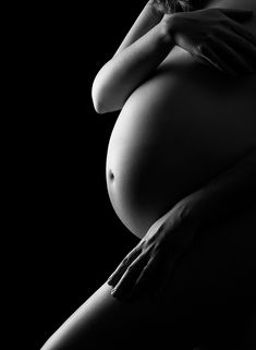 a pregnant woman's belly in black and white with her hands on her hips