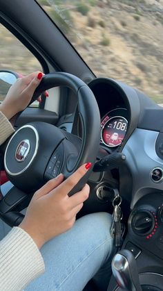 a woman driving a small car with her hands on the steering wheel