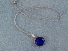 "This faceted dark blue sapphire is set in a round floral designed bezel frame. A fan shaped bail holds this deep blue gem on an oxidized silver cable link chain, closed with a lobster claw clasp. The 18mm (3/4\") Czech glass gem is dark blue and has many facets that reflect the light. The chain in 20\" in length. Chain length can be ordered from 16\" up to a 24\" with no additional cost. Just message me with your request at time of purchase. This lovely sparkling cobalt blue necklace would enha Victorian Style Blue Round Pendant Jewelry, Victorian Blue Gemstone Necklace, Victorian Round Faceted Jewelry, Victorian Faceted Round Jewelry, Formal Royal Blue Round Jewelry, Blue Round Faceted Jewelry, Blue Faceted Round Jewelry, Faceted Round Sapphire Jewelry, Round Sapphire Cabochon Necklaces