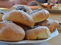 a white plate topped with donuts covered in powdered sugar next to other plates